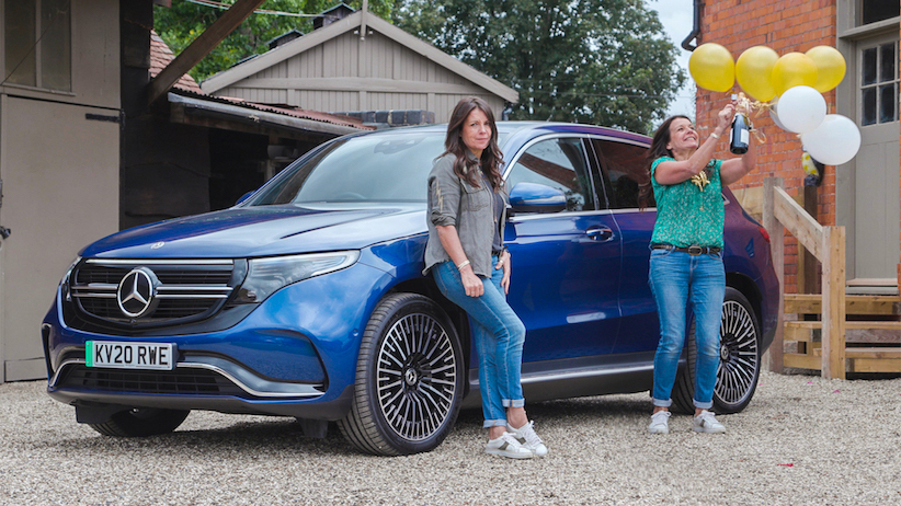 Mercedes EQC, blue, with two Ginny Buckleys, one with party paraphernalia